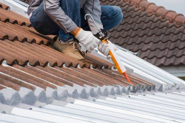 Roofer applying sealant to fix a leaking tile roof in Hamilton